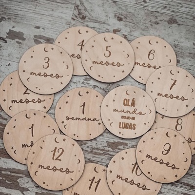 Placas redondas de madeira com gravações em português sobre meses e uma semana, decoradas com estrelas e luas.