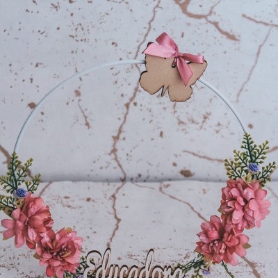 Aro decorativo branco com flores artificiais cor-de-rosa e verde, selo de flor de madeira com fita rosa e palavra 'Educadora' em madeira numa base