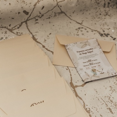 Envelopes creme com letras douradas e convite formal em superfície rachada