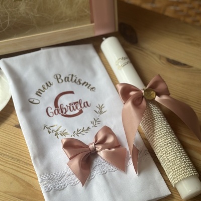 Vela e pano de batismo decorados com laços cor rosa e bordados com o nome Gabriela