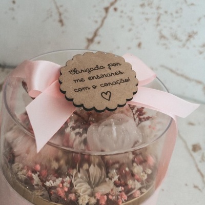 Caixa redonda rosa com flores dentro e etiqueta com mensagem de agradecimento.