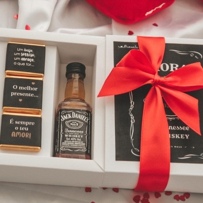 Conjunto de presente com mini garrafa de whiskey e blocos com texto em caixa branca com laço vermelho