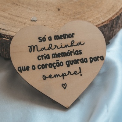 Placa de madeira coração com frase para madrinha, sobre superfície de madeira e tecido azul