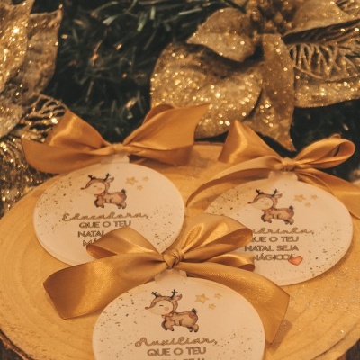 Enfeites de Natal redondos com laços dourados e ilustração de rena sobre madeira
