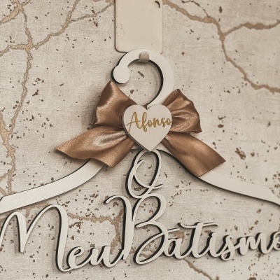 Cabide branco decorativo com laço dourado e texto O Meu Batismo