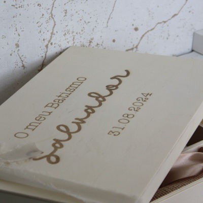 Caixa branca com tampa escrita dourada sobre superfície clara texturada