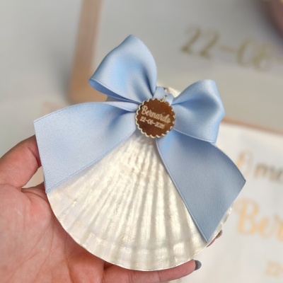 Concha decorativa com laço azul e medalha personalizada