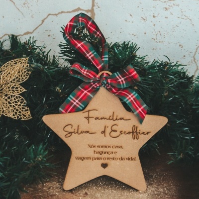 Ornamento de estrela em madeira com fita xadrez pendurado numa guirlanda verde
