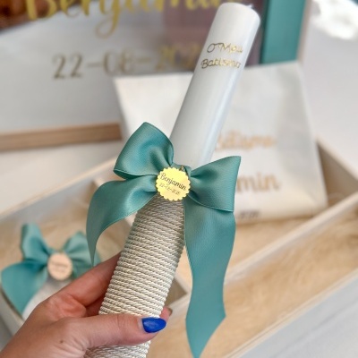 Vela branca decorada para batismo com laço verde-azulado e pendente dourado com nome Benjamin