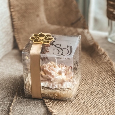 Vela flor cor de rosa em embalagem transparente com fita dourada sobre juta