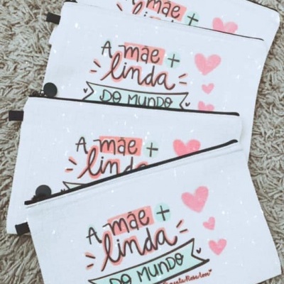 Necessaires brancas com fecho preto e texto colorido sobre superfície bege