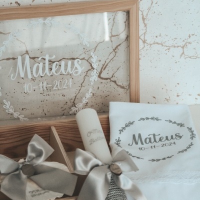 Conjunto de velas decorativas e lenço branco personalizados com nome e data numa caixa de madeira e moldura de vidro