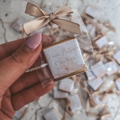 Lembrança de chocolate personalizada para batizado com fita bege em embalagem transparente.