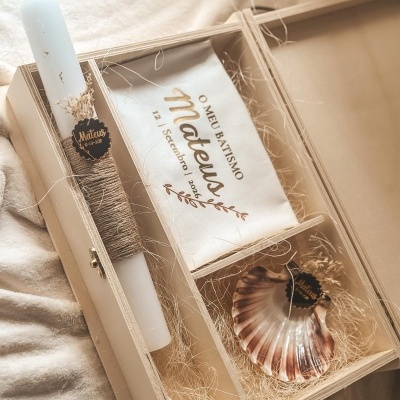 Conjunto de batismo com vela, concha e toalha numa caixa de madeira