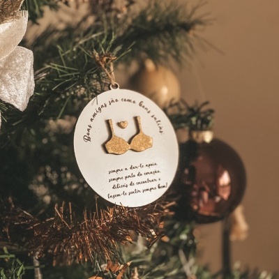Enfeite de Natal redondo branco com sutiã dourado e texto em português pendurado na árvore