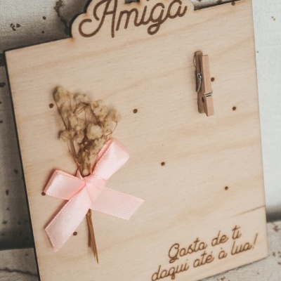 Placa de madeira clara com flores secas e mensagem para amiga