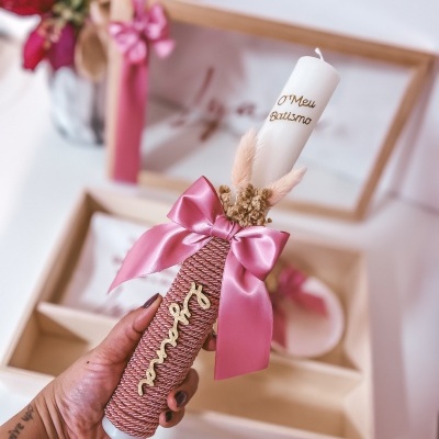 Vela de batismo branca decorada com fio rosa, laço de cetim rosa e flores secas.