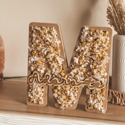 Letra M decorativa em MDF com flores secas e palavra Adoro-te sobre móvel.