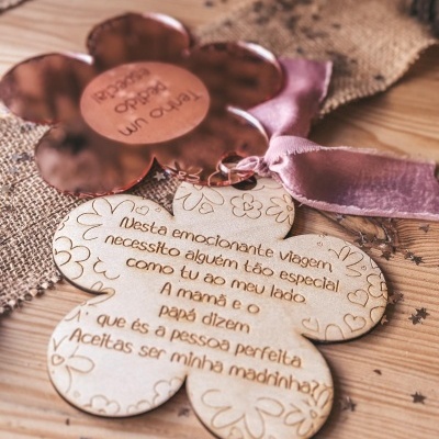 Placas em forma de flor em metal cobre e madeira com inscrições, fita de veludo rosa, sobre tecido de juta e superfície de madeira