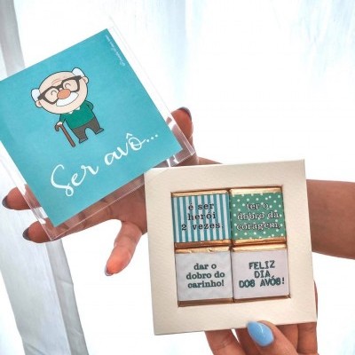 Caixa de chocolates com mensagens para o Dia dos Avós e cartão azul com desenho de avô e texto 'Ser avô...'
