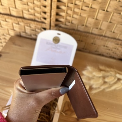 Carteira castanha aberta com embalagem branca ao fundo e superfície de madeira