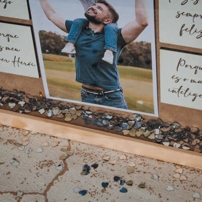 Moldura de madeira com foto de homem e criança e texto em português sobre fundo de pedras pequenas