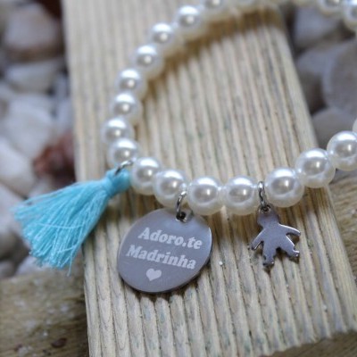 Pulseira branca perolada com pendentes e tassel azul claro sobre madeira