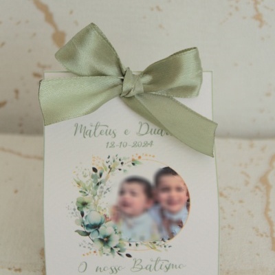 Caixa branca com laço verde e foto de duas crianças alusiva a batismo.