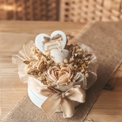 Arranjo decorativo de flores e corações em caixa redonda com laço dourado