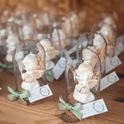 Figuras de anjo em resina sob redomas de vidro numa mesa de madeira