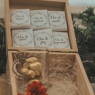 caixa de madeira com saquinhos de chá e copo com corações dourados e flor