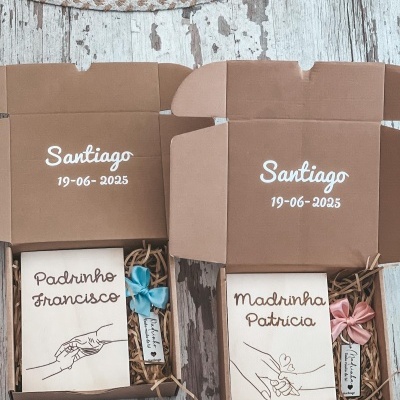 Caixas de presente castanhas com pacotes personalizados para padrinho e madrinha em branco com ilustrações de mãos, em fundo de madeira clara.