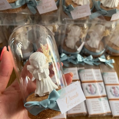 Miniatura de anjo branco em cúpula de vidro com base de cortiça e laço azul, etiqueta 'Obrigado Vicente 14.05.2023' e caixas de chocolate