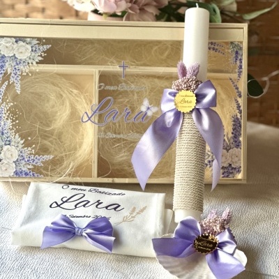 Conjunto de batismo com vela decorada, tecido branco e concha, todos decorados com laços lilás