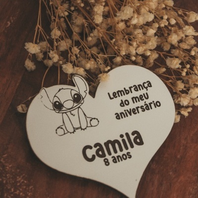 Cartão coração branco com desenho de Stitch e texto em português sobre superfície de madeira e flores secas