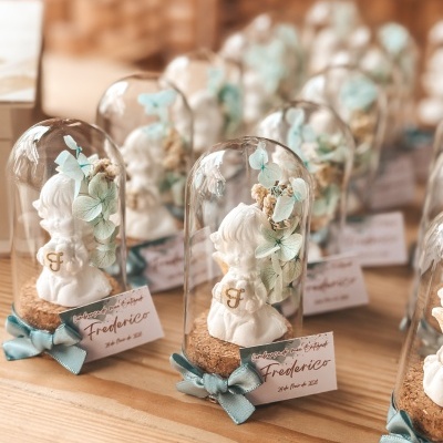 Lembranças de batizado com esculturas de anjos e flores dentro de domos de vidro em bases de cortiça