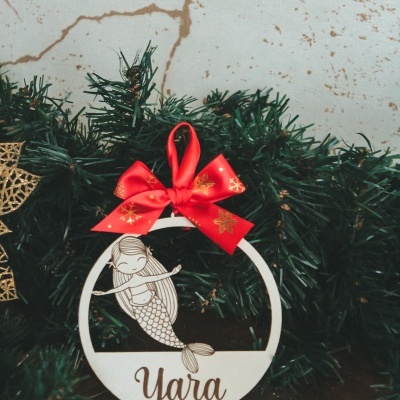 enfeite de Natal redondo em madeira branca com sereia e nome Yara decorado com laço vermelho