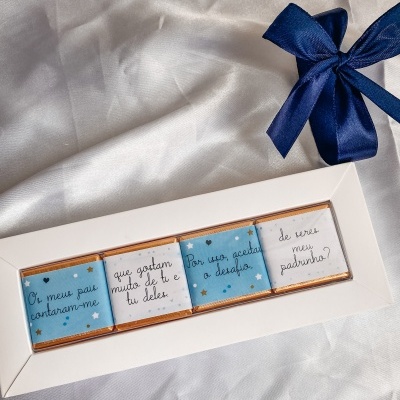 Conjunto de chocolates com mensagens em português numa caixa branca com laço azul