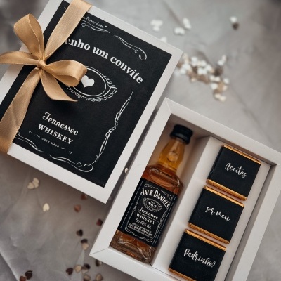 caixa branca com mini garrafa Jack Daniel's e chocolates com mensagem em fundo cinza