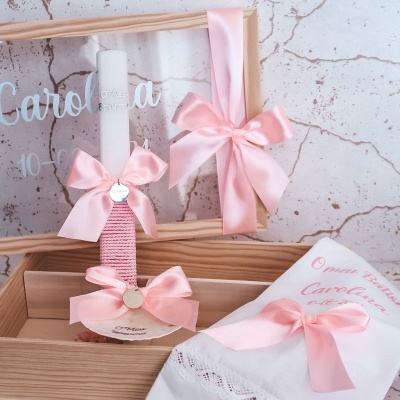 Conjunto de lembranças de batizado com vela, toalha branca bordada, fita rosa e caixa de madeira com vidro com inscrições.