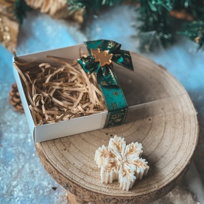 Caixa branca decorativa com vela em forma de floco de neve sobre base de madeira