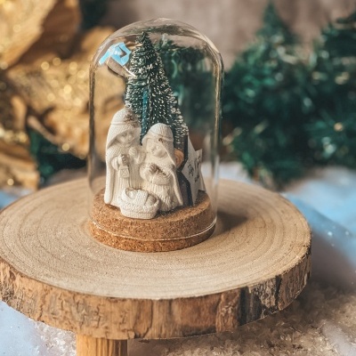 Presépio natalício em miniatura sob campânula de vidro com base de cortiça