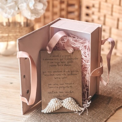 Caixa rosa com cartão manuscrito e ornamentos de asas brancas
