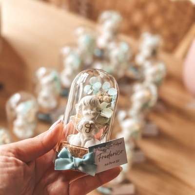 Anjo decorativo branco dentro de cloche de vidro com base de cortiça e laço azul