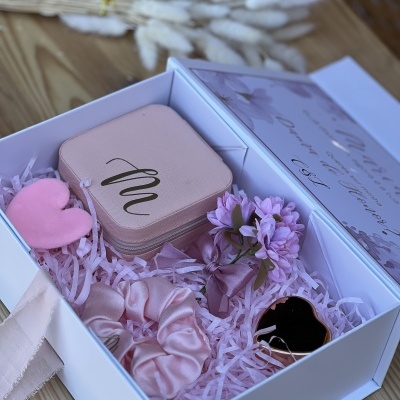 Caixa branca com embalagem rosa e itens decorativos rosa e lilás