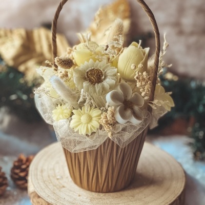 Cesta decorativa com flores artificiais amarelas e brancas sobre base de madeira redonda
