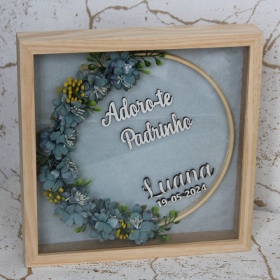 quadro decorativo com flores artificiais e texto 'Adoro-te Padrinho Luana 12-05-2024' em fundo cinza, moldura de madeira