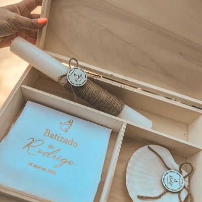 Caixa de madeira com vela branca, lenço branco com texto dourado e concha decorativa