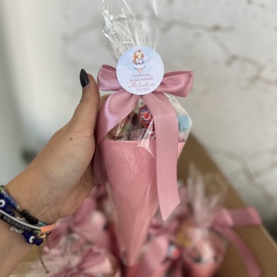 Cone de papel rosa com laço e etiqueta para lembrança de batizado embrulhado em plástico