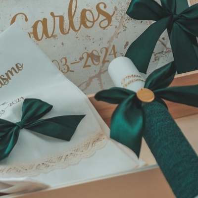 Itens para batismo com lenço bordado, vela e caixas com laços verdes e fundo com nome Carlos.